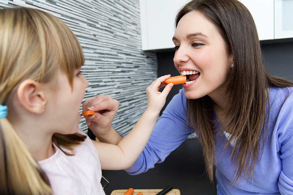 mother feeding her child a carrot